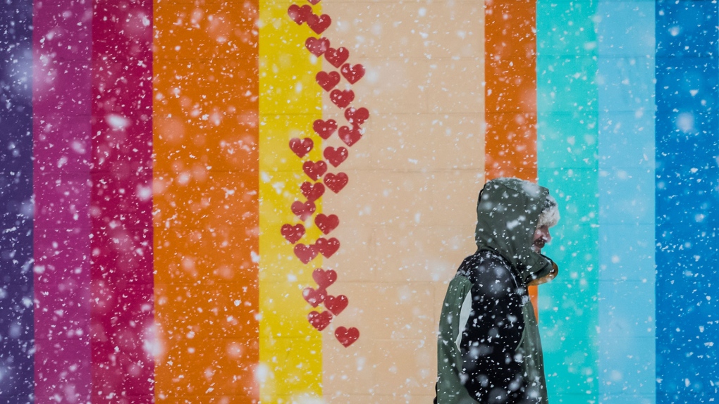 A man stands outside a brightly painted building as heavy snow falls in Vancouver, on Sunday Feb. 10, 2019. (Darryl Dyck / THE CANADIAN PRESS)