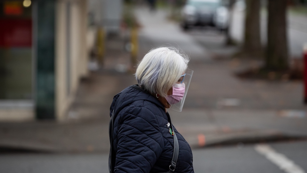 A person wears a face mask and shield to curb the spread of COVID-19 while walking in Vancouver on Sunday, Dec. 6, 2020. (Darryl Dyck / THE CANADIAN PRESS)