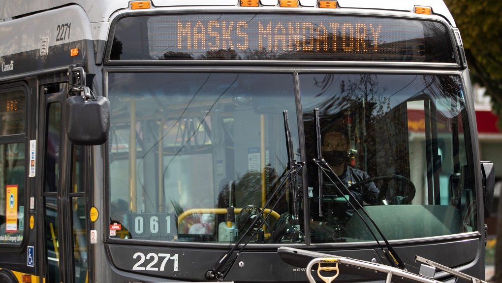 A bus driver wears a face mask to curb the spread of COVID-19 as the digital sign on the front of the bus reminds passengers that masks are mandatory on public transit, in Vancouver, Sunday, Aug. 30, 2020. (Darryl Dyck / THE CANADIAN PRESS)