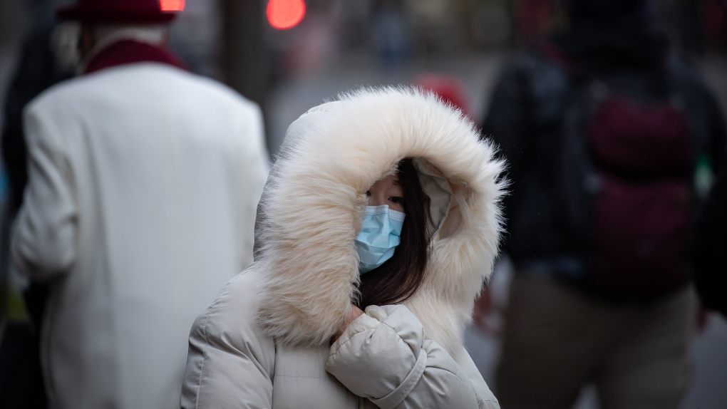 A person bundled up in a heavy jacket for the cold weather wears a face mask to curb the spread of COVID-19 in Vancouver, on Tuesday, December 21, 2021. THE CANADIAN PRESS/Darryl Dyck 