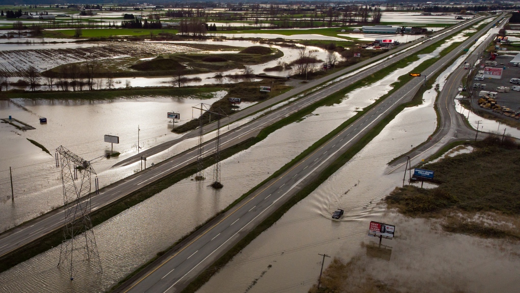 A motorist drives on a service road along the closed Trans-Canada Highway as floodwaters fill the ditches beside the highway and farmland in Abbotsford, B.C., on Wednesday, December 1, 2021. THE CANADIAN PRESS/Darryl Dyck 