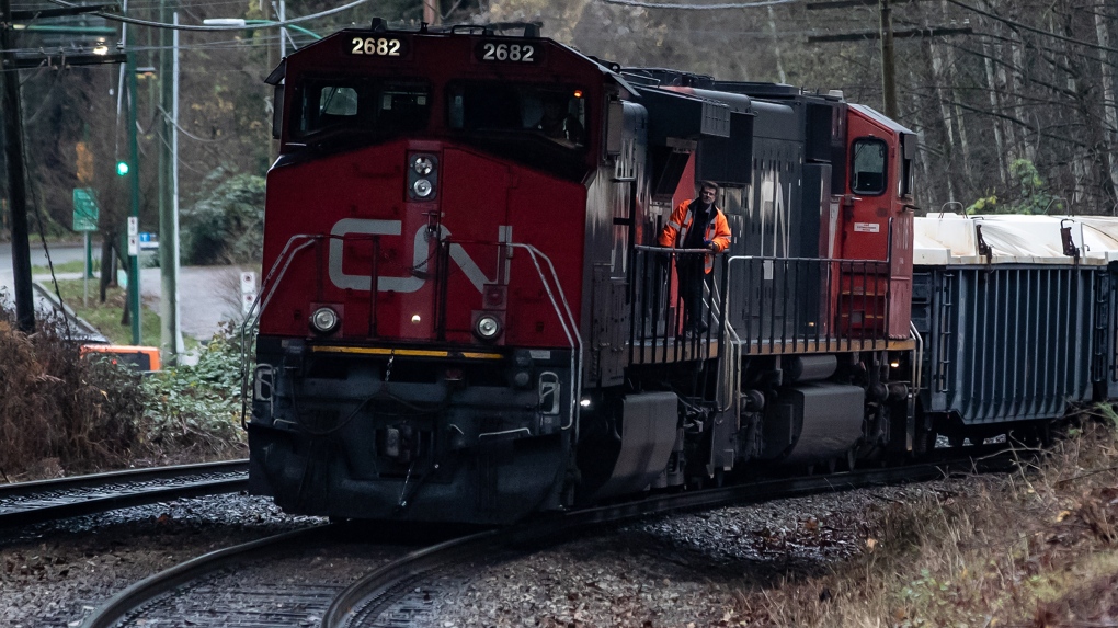 A CN rail worker stands on an idle locomotive as protesters opposed to the Trans Mountain pipeline expansion block rail lines, in Burnaby, B.C., on Friday, November 27, 2020. THE CANADIAN PRESS/Darryl Dyck 