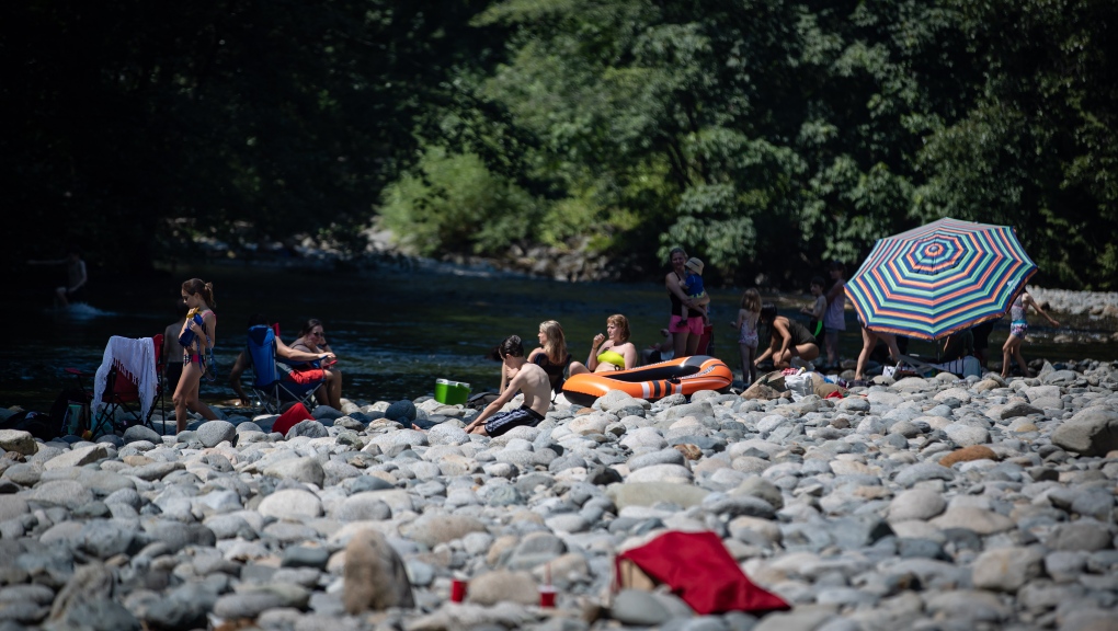 People sit on rocks while cooling off in the frigid Lynn Creek water in North Vancouver, B.C., on Monday, June 28, 2021. THE CANADIAN PRESS/Darryl Dyck 