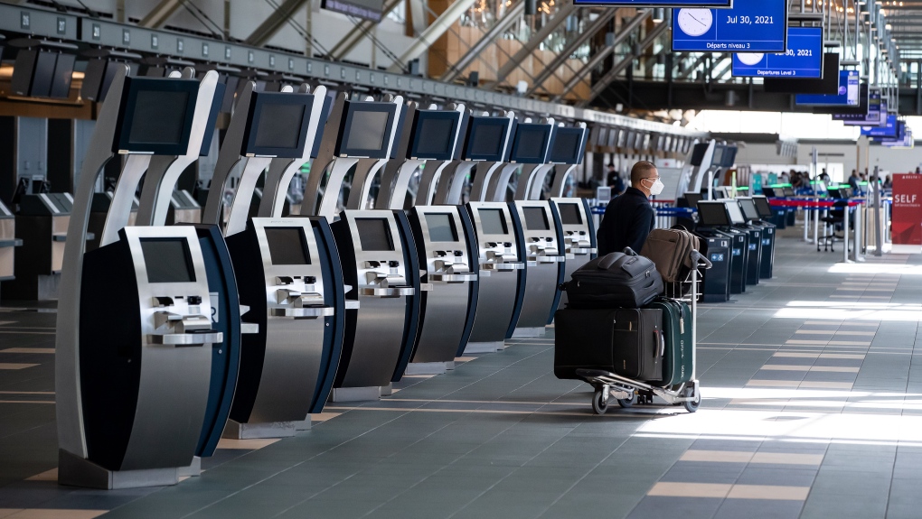 A traveller waits next to check-in kiosks not currently in use at Vancouver International Airport, in Richmond, B.C., on Friday, July 30, 2021. 