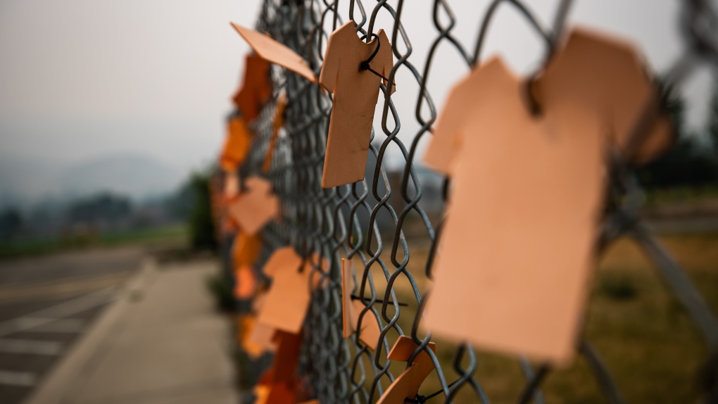 Cutouts of orange T-shirts are hung on a fence outside the former Kamloops Indian Residential School, in Kamloops, B.C., on Thursday, July 15, 2021. (Darryl Dyck / THE CANADIAN PRESS)
