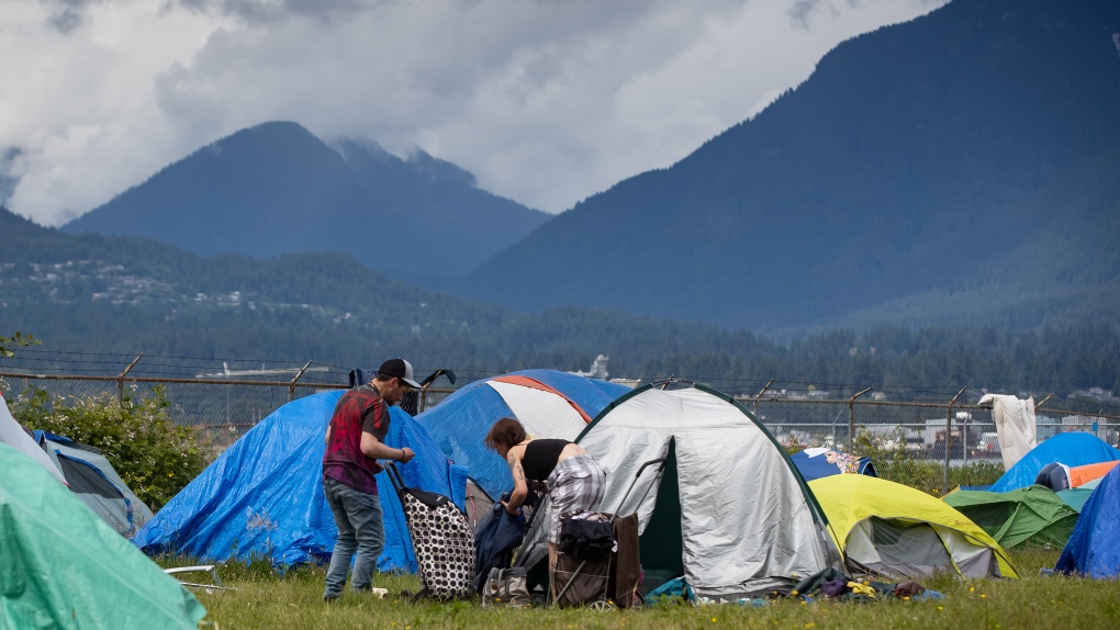 People are seen outside a tent at a homeless camp on Port of Vancouver property adjacent to Crab Park, in Vancouver, Saturday, June 13, 2020. (Darryl Dyck / THE CANADIAN PRESS)