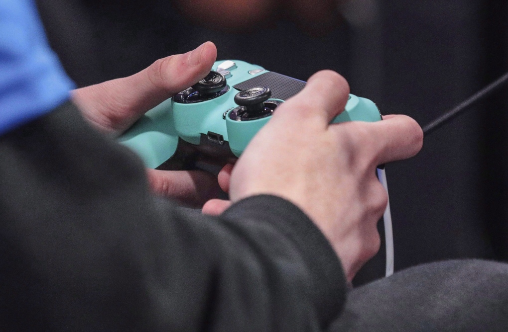 A competitor holds a Playstation 4 controller during a July 2019 gaming event in New York. (THE CANADIAN PRESS/AP/Bebeto Matthews)