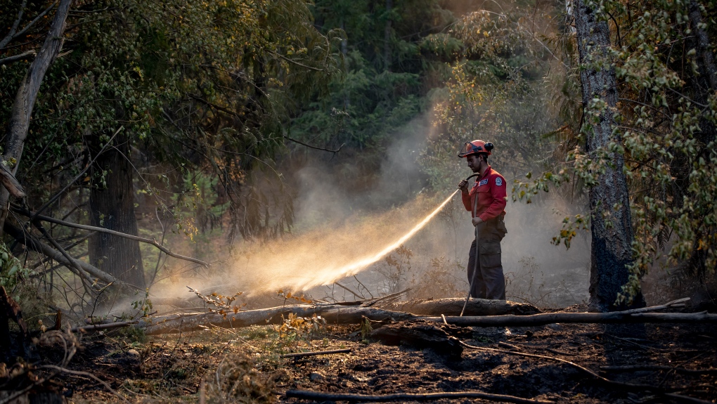 Wildland firefighter Sasha Terhoch sprays water on hot spots remaining from a controlled burn the B.C. Wildfire Service conducted to help contain the White Rock Lake wildfire on Okanagan Indian Band land, northwest of Vernon, B.C., on Wednesday, August 25, 2021. THE CANADIAN PRESS/Darryl Dyck