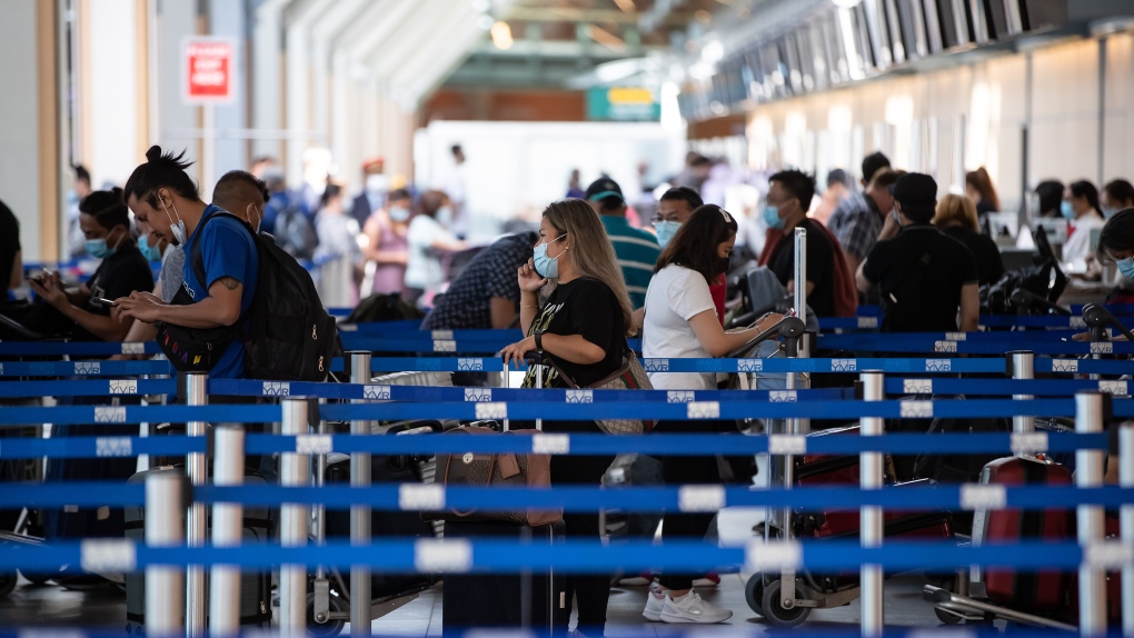 Travellers wait in line to check-in for a flight at Vancouver International Airport, in Richmond, B.C., on Friday, July 30, 2021. THE CANADIAN PRESS/Darryl Dyck
