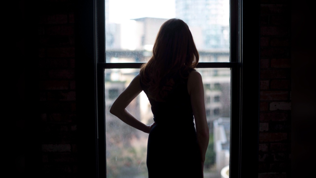 An escort who gave her name as SB is silhouetted against a window as she poses at a downtown Vancouver apartment, Sunday, Feb. 12, 2017. THE CANADIAN PRESS/Jonathan Hayward