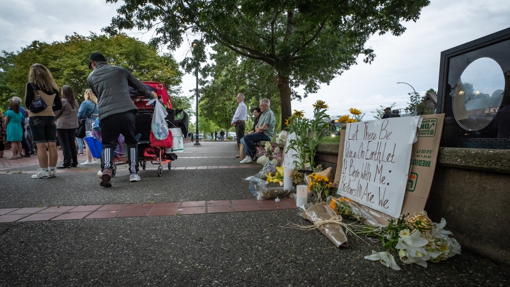 A person pushes a cart of belongings past a memorial for Steven Furness and Paul Wynn, the two men who were killed by a gunman during a series of attacks on homeless people last month, in Langley, B.C., on Wednesday, August 3, 2022. THE CANADIAN PRESS/Darryl Dyck