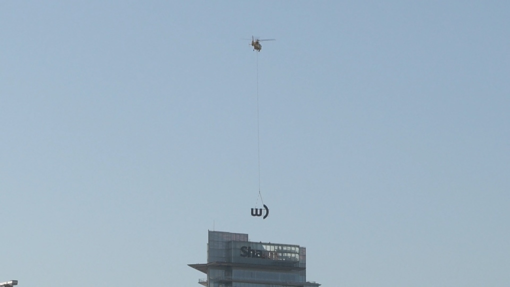 A helicopter was called in to help remove the Shaw logo from a tower in downtown Vancouver on Friday, May 26, 2023. (CTV)